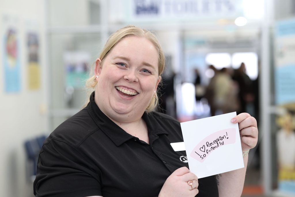 Blond woman smiling and holding label