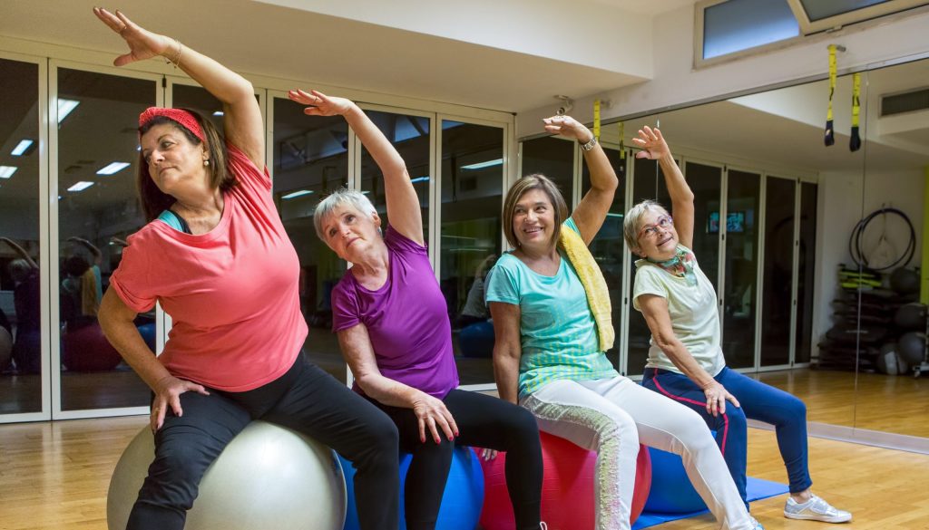 Gruppo di quattro donne che fanno stretching su palle da ginnastica