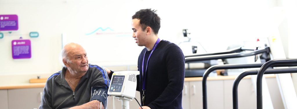 Man seated in walker talking to health professional