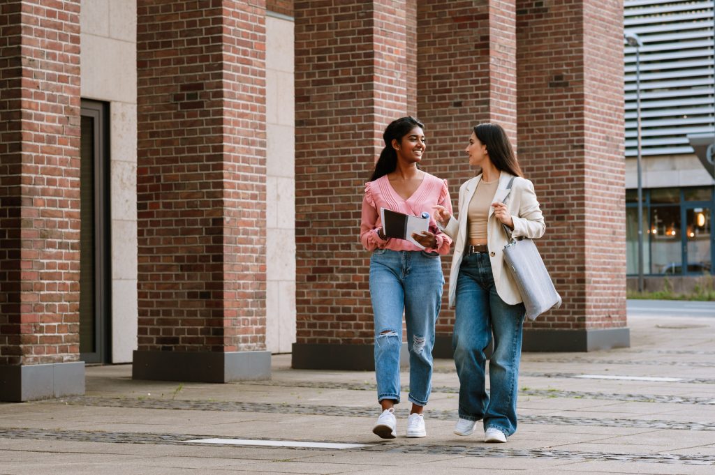 Due donne multinazionali parlano insieme mentre camminano in una strada della città