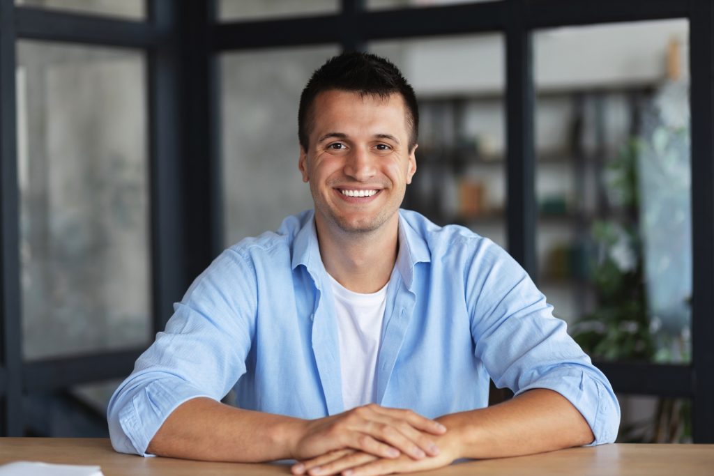 Man smiling to camera in blue shirt