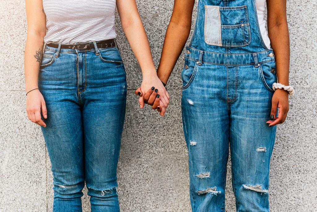 two people holding hands wearing denim, faces not seen