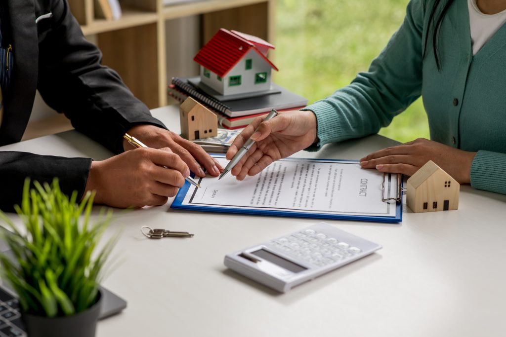Hand leaning over a clipboard with a pen to sign documents