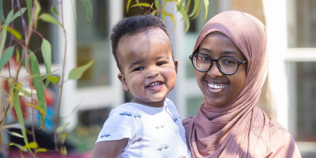 Omm ta’ sfond Afrikan bil-hijab ma’ tifel żgħir barra