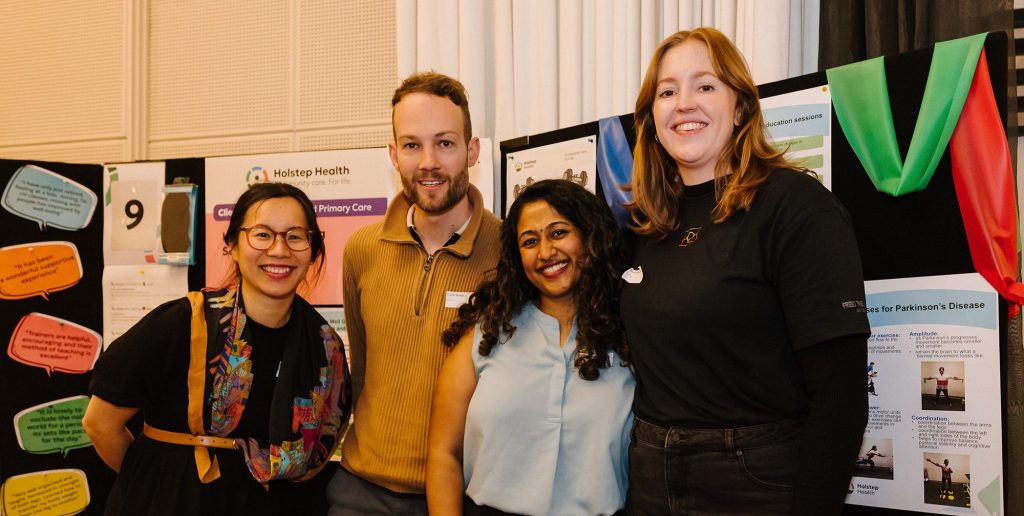 Three women and a man standing smiling at the camera in front of an expo stall