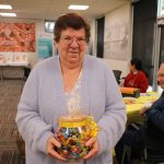 An older woman with brown hair is holding a jar of jelly beans
